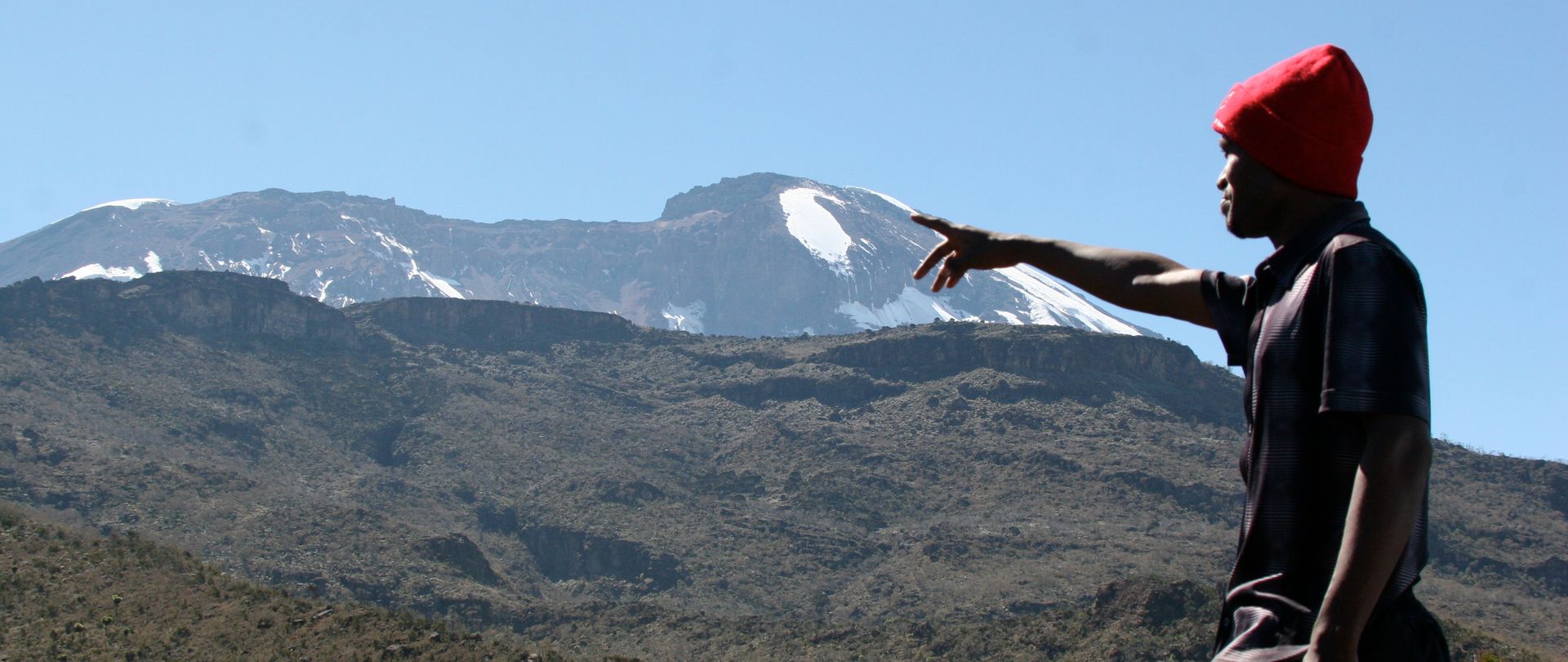 Porteur pointant le sommet du Kilimandjaro