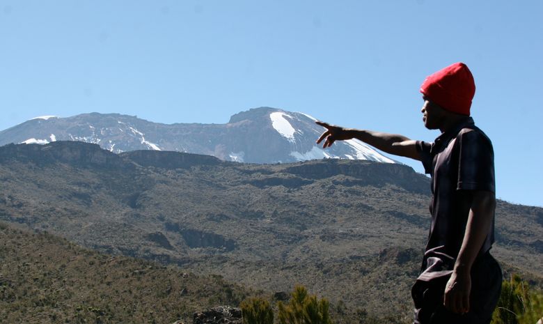 Porteur pointant le sommet du Kilimandjaro